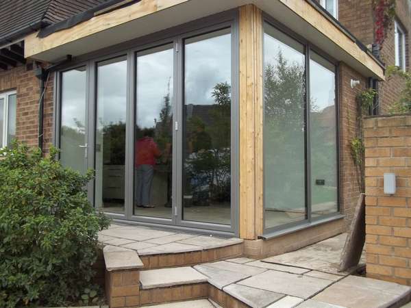 Installtion of Centor C1 Aluminium Bi folding doors with returning fixed window i Hyde Cheshire . The photo is show how the corner after installtion requires matching Aluminium pressing to form a finish . The pressing is the area of the installtion you as